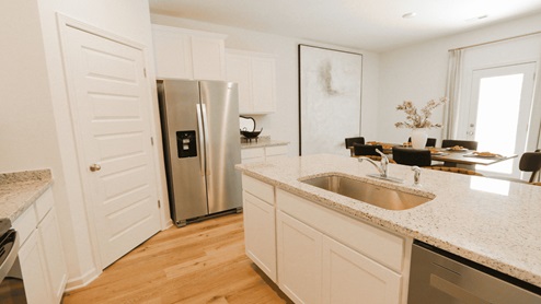 Tradition Package - 1tradition_kitchen: A contemporary kitchen equipped with a stainless-steel fridge, microwave, and electric stove. 2Traditionkitchen2: Side view of another kitchen with the dining room on the left and pantry door on the right. 3TraditionKitchen3: Perspective of the kitchen from the left side of the kitchen island with a view of the front hallway and bar stools. 4TraditionSink: A kitchen island with a farmhouse sink and a view to the dining room. 5traditionalbathroom: A double vanity featuring two mirrors and granite countertops. 6solarboard1: A close-up image of solar board 7solarboard2: A view from the inside of the trusses and solar board.