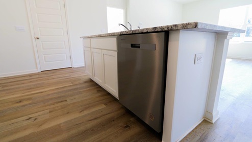 A stylish kitchen showcasing granite counter tops, white cabinetry paired with stainless steel appliances, emphasizing a clean and modern design.
