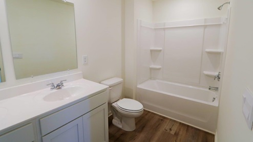 A well-organized bathroom with essential fixtures: a toilet, sink, and bathtub, emphasizing simplicity and utility.