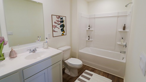 A well-organized bathroom with essential fixtures: a toilet, sink, and bathtub, emphasizing simplicity and utility.
