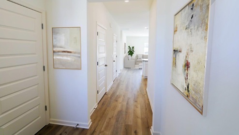 A well-lit hallway lined with white doors, complemented by elegant wood flooring that enhances the space's warmth.