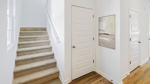 A well-lit hallway lined with white doors, complemented by elegant wooden flooring that enhances the space.