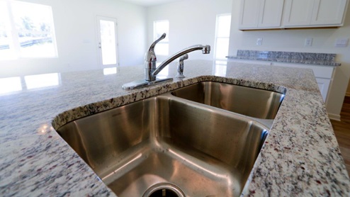 A stylish kitchen showcasing granite counter tops, white cabinetry paired with stainless steel appliances, emphasizing a clean and modern design.