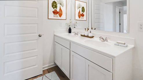 A modern bathroom featuring white cabinets and a large mirror, creating a bright and spacious atmosphere.