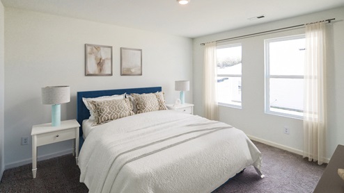 A spacious empty room featuring soft carpet flooring and clean white walls, creating a bright and airy atmosphere.