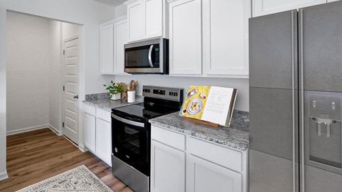 A stylish kitchen showcasing granite counter tops, white cabinetry paired with stainless steel appliances, emphasizing a clean and modern design.