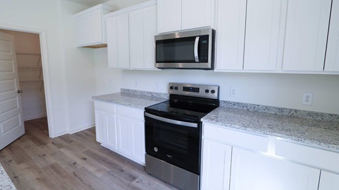 Modern kitchen featuring sleek white cabinets and granite countertops, perfect for cooking and entertaining. KITCHEN_3- Bright and airy open-concept living space featuring modern finishes and abundant natural light.