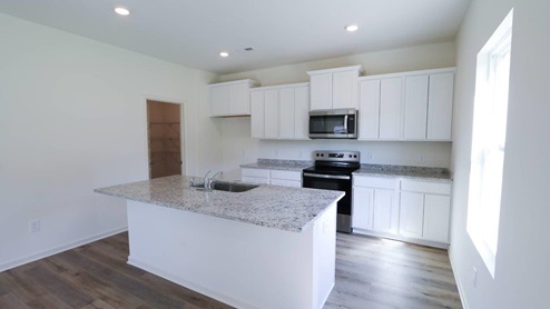Modern kitchen featuring sleek white cabinets and granite countertops, perfect for cooking and entertaining. KITCHEN_3- Bright and airy open-concept living space featuring modern finishes and abundant natural light.