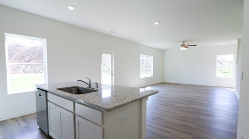 Modern kitchen featuring sleek white cabinets and granite countertops, perfect for cooking and entertaining. KITCHEN_3- Bright and airy open-concept living space featuring modern finishes and abundant natural light.