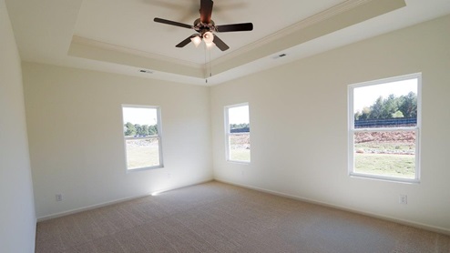 Bright and spacious bedroom featuring large windows and a ceiling fan for optimal comfort. The bedroom is well-lit and has ample space, with large windows that let in plenty of natural light. It includes a ceiling fan to ensure optimal comfort and air circulation.
