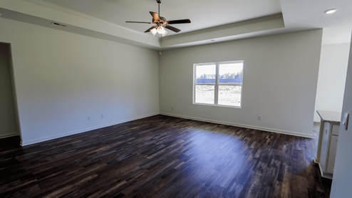Spacious living room featuring elegant wood flooring and ample natural light from large windows. The living room is spacious and showcases elegant wood flooring. It is filled with ample natural light streaming in through large windows.
