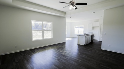Spacious living room featuring elegant wood flooring and ample natural light from large windows. The living room is spacious and showcases elegant wood flooring. It is filled with ample natural light streaming in through large windows.