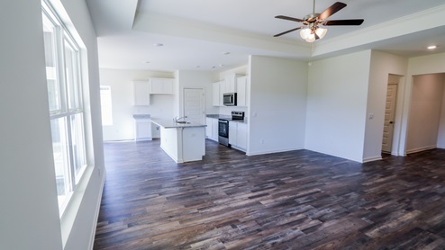 Spacious living room featuring elegant wood flooring and ample natural light from large windows. The living room is spacious and showcases elegant wood flooring. It is filled with ample natural light streaming in through large windows.