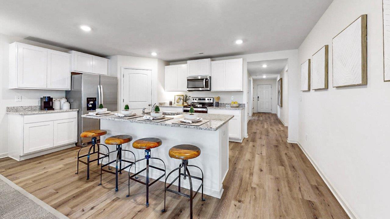 The kitchen is a spacious open concept area with stainless steel appliances. It includes an oversized kitchen island with barstools for seating and food preparation. Additionally, there is a convenient walk-in pantry for storage.