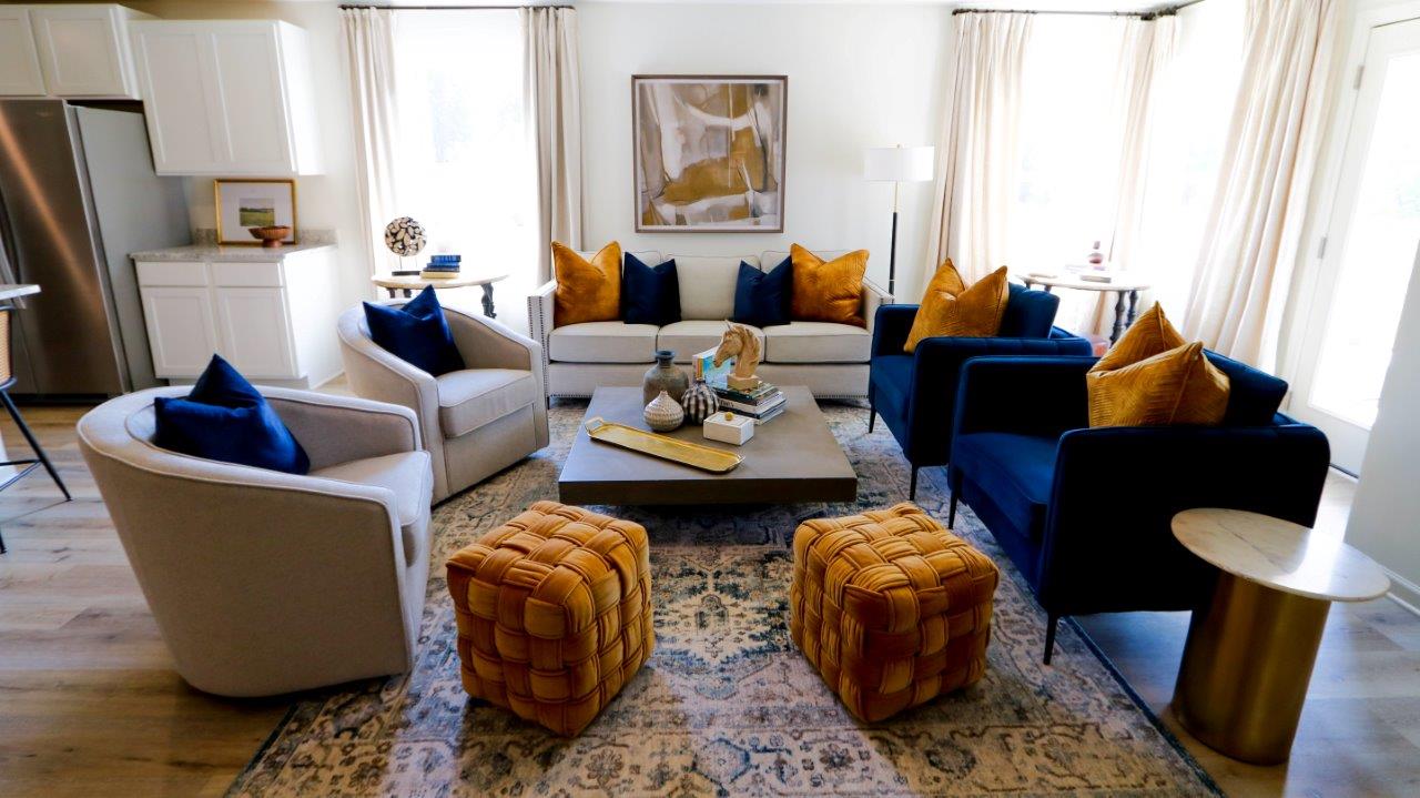 The living room has space for a full 3-person couch, 4 armchairs, side tables, and a spacious coffee table. It is here shown staged with a full suite of living room furniture.