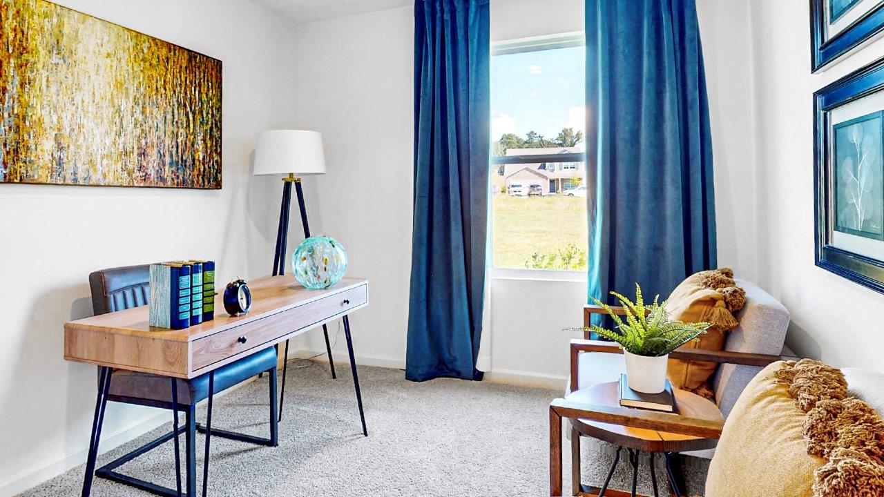Bedroom currently used as an office with a large desk and two sitting chairs