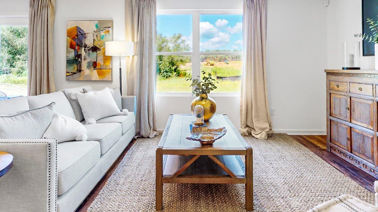 Spacious living room that features a couch, two poofs, a coffee table, a media consol and an accent chair