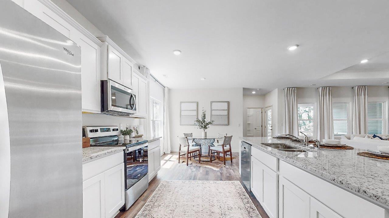 Different view of the kitchen shows off the large kitchen island, the stainless steel appliances and the breakfast nook that is right off the kitchen