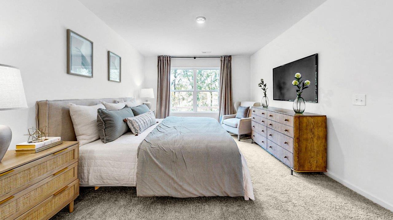 Bright primary bedroom fits a king sized bed, 2 nightstands, a dresser, and an accent chair