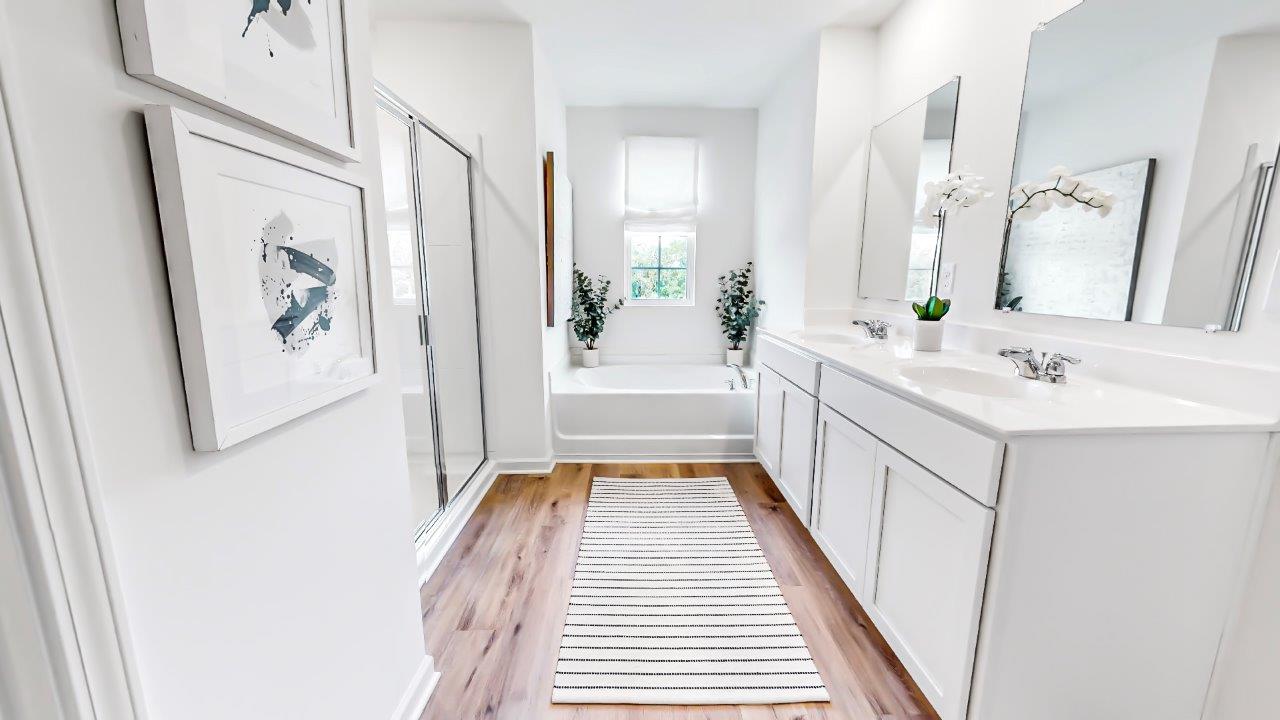 The large primary bathroom has a double vanity, a walk in shower, and a large garden tub