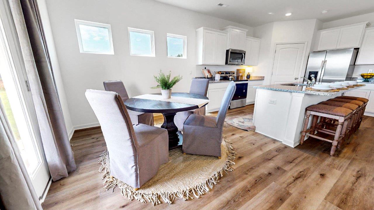 A nice breakfast nook with a round table and chairs right off of the kitchen