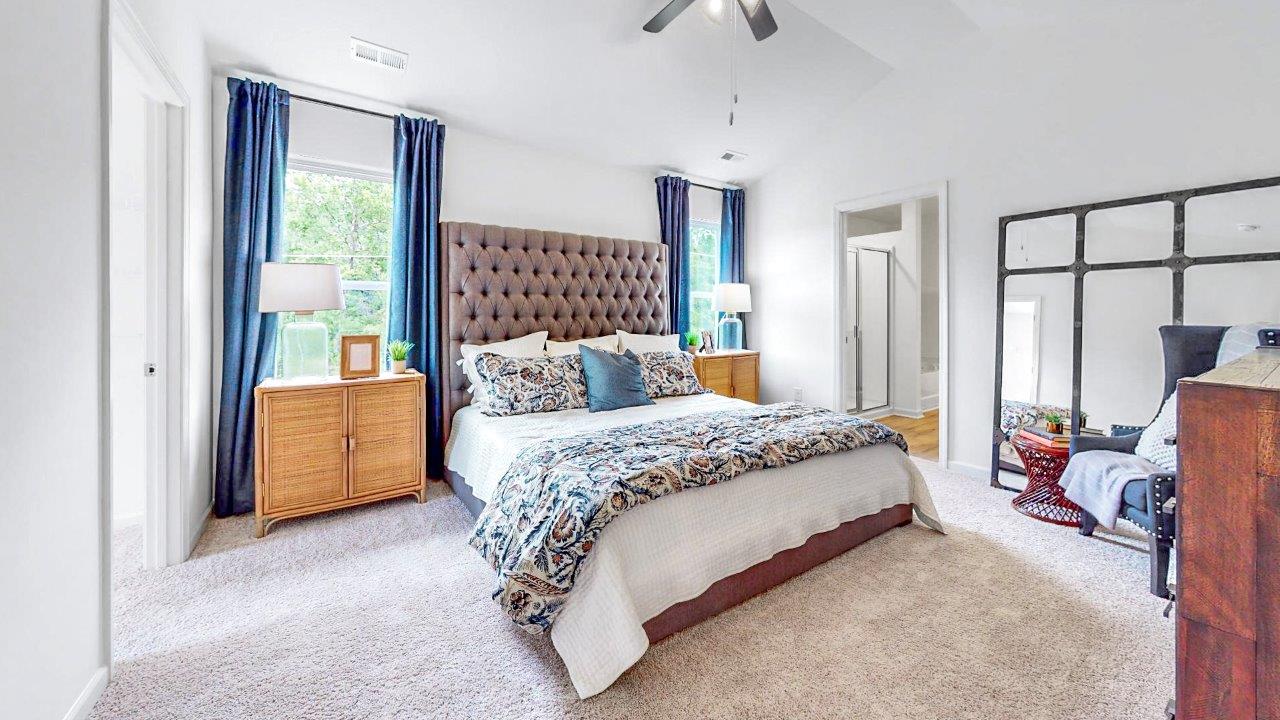 Large primary bedroom with king sized bed, two oversized nightstands and a dresser