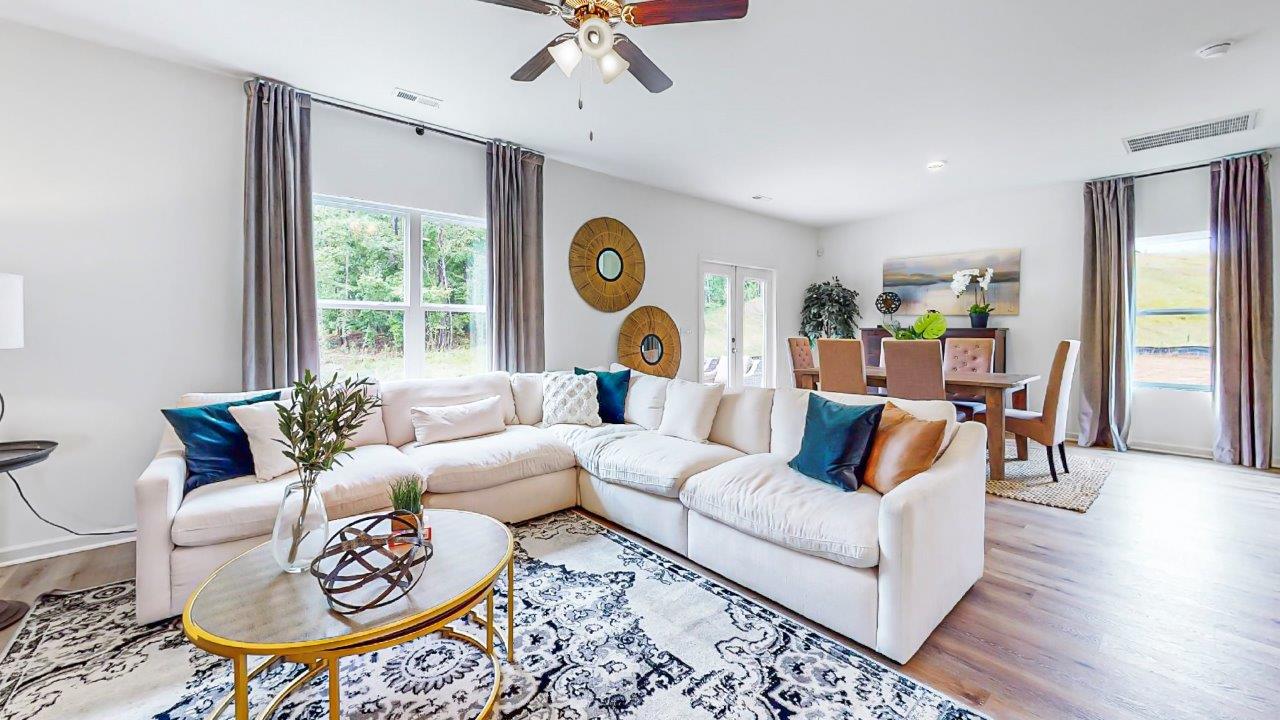 the large open concept living room shows a sectional couch that opens to the breakfast nook behind it
