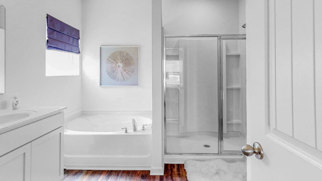 the primary bathroom includes a double sink vanity, large garden tub and a walk in shower