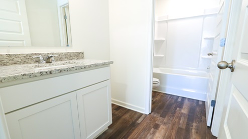 The upstairs bathroom has a tub shower combo and toilet are located behind a door, so the vanity can still be accessed when the bathroom is in use.