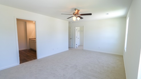 A view of the primary bedroom, leading into the primary bathroom.