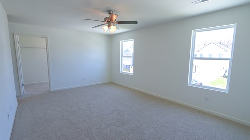 The primary bedroom features large windows which allow for a lot of natural light to flow in.