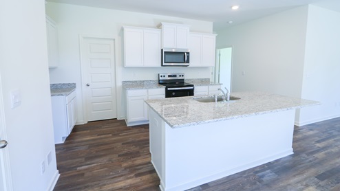The kitchen features stainless steel appliances and a large island with an eating area.