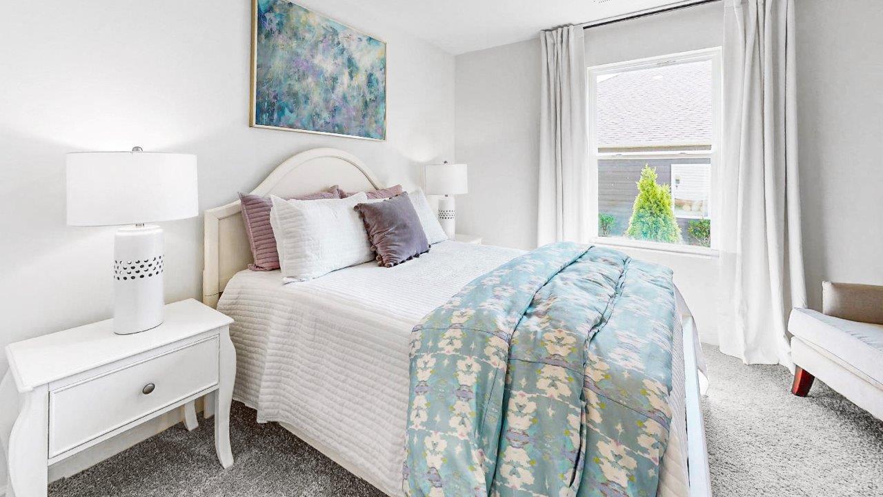 Second bedroom features a bed with 2 nightstands, a large window and accent chair