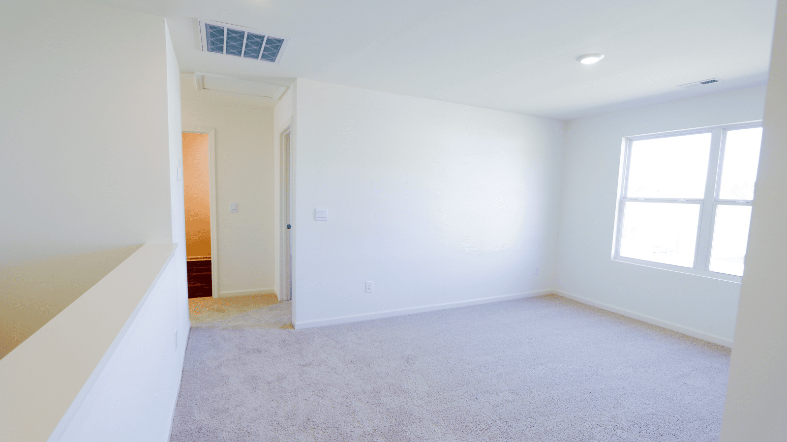 Bright, empty room with light beige carpet and large windows, showcasing potential for interior decoration.