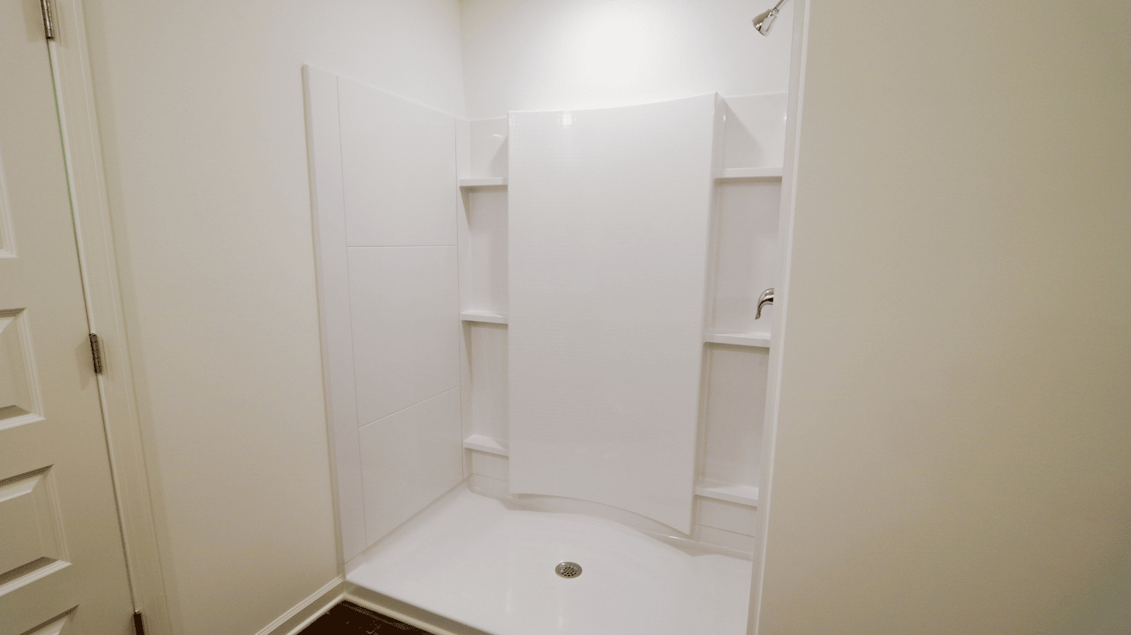White walk-in shower with built-in shelves and a curved privacy curtain, designed for easy access and grab bars.