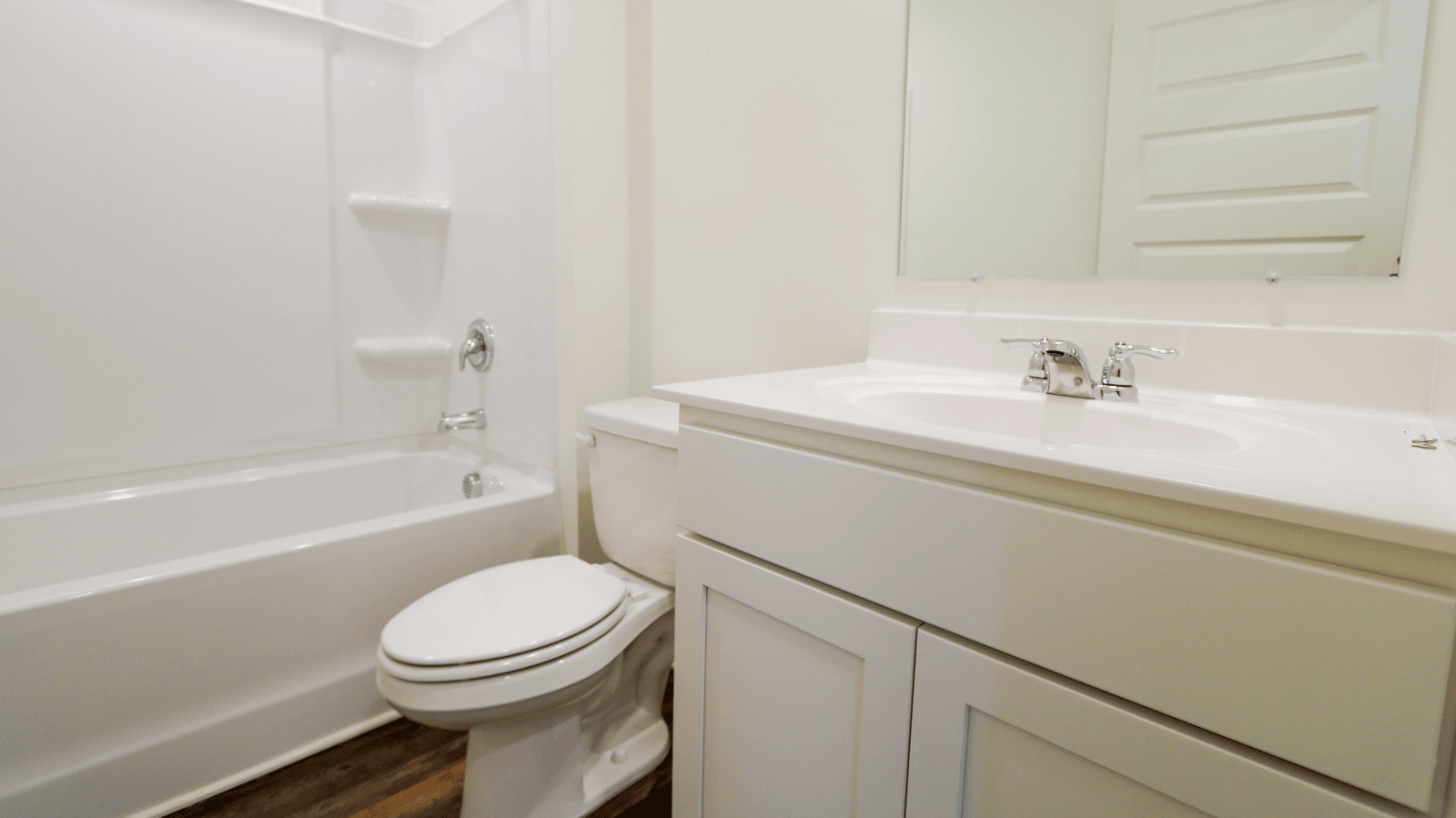 Modern bathroom featuring a double vanity with mirrors, light-colored walls, and a doorway leading to a closet space.