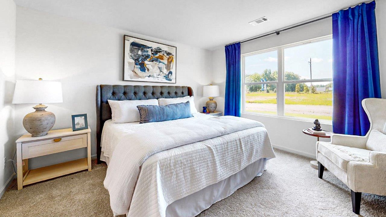 Aldridge – Primary Bedroom – The primary bedroom suite features a king sized bed, two nightstands, a dresser and an accent chair