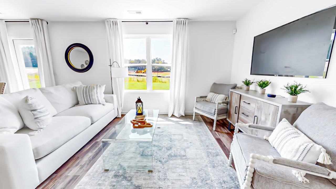 Living room features a couch, coffee table, two accent chairs and a media consol with TV