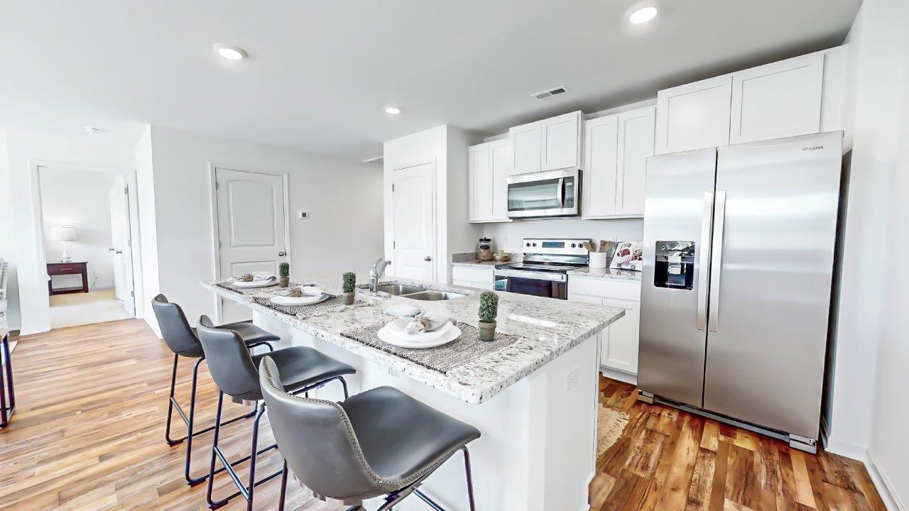 Open concept kitchen features a large island with white cabinets and stainless steel appliances.