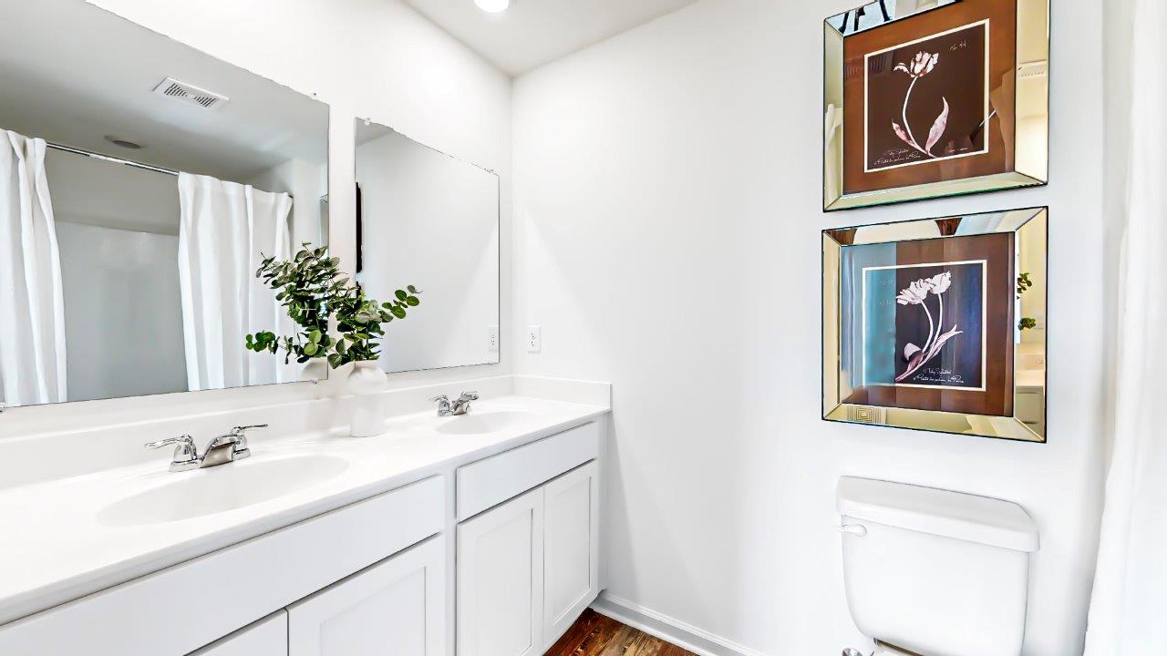 Primary bathroom features a double sink vanity, toilet and tub shower