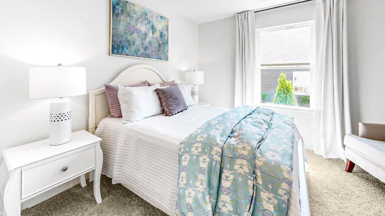 Guest bedroom features a bed with 2 nightstands, a large window and accent chair