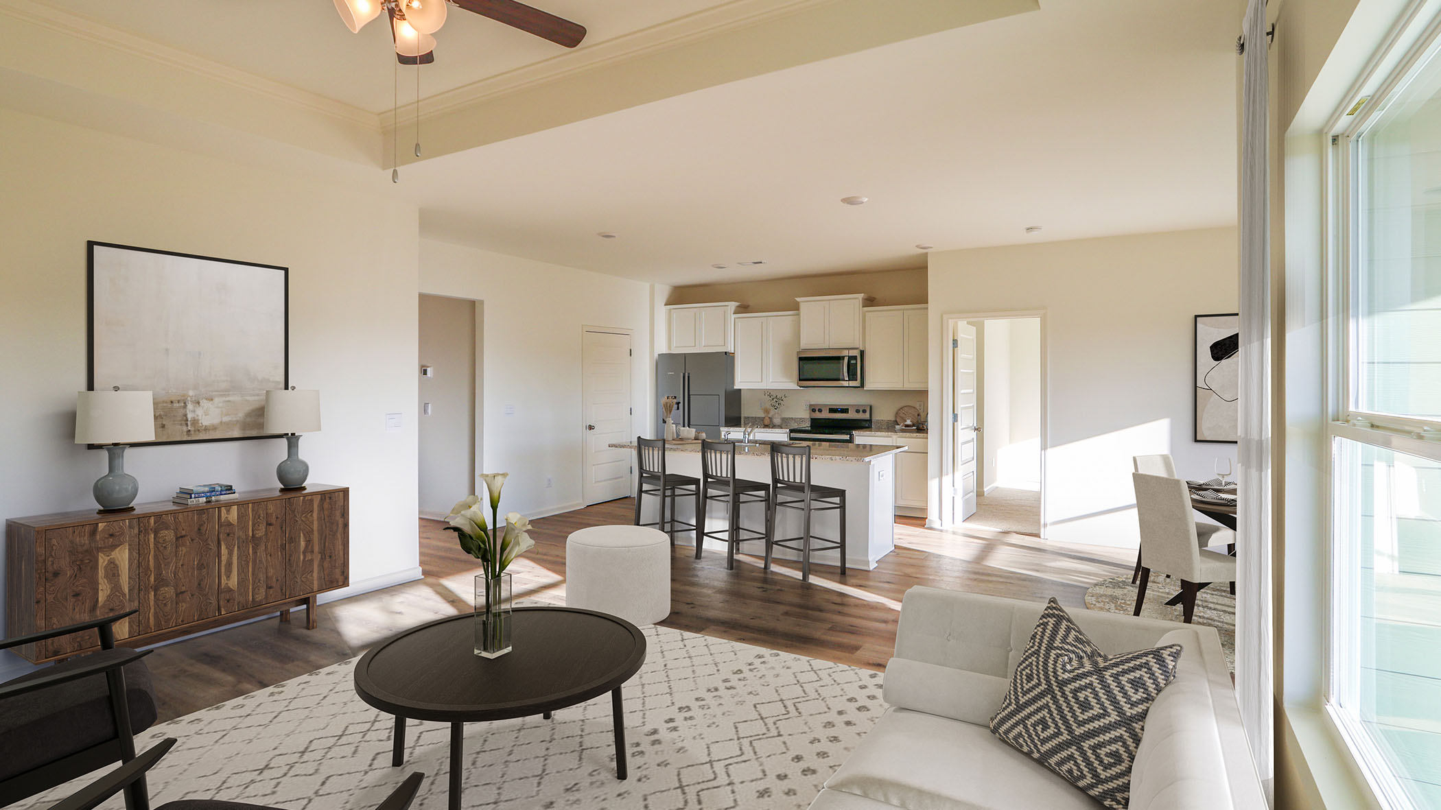 Modern open-concept living room and kitchen with neutral tones, featuring cozy seating, a wooden dining table, and contemporary decor, illuminated by natural light from large windows.
