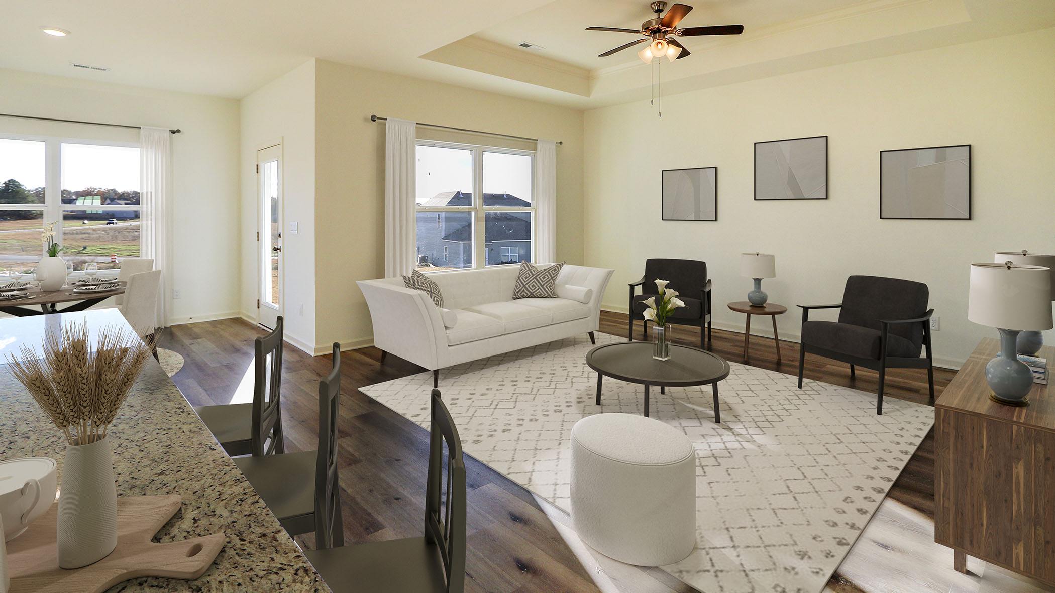 A cozy living room featuring a ceiling fan, seamlessly connected to a modern kitchen area.