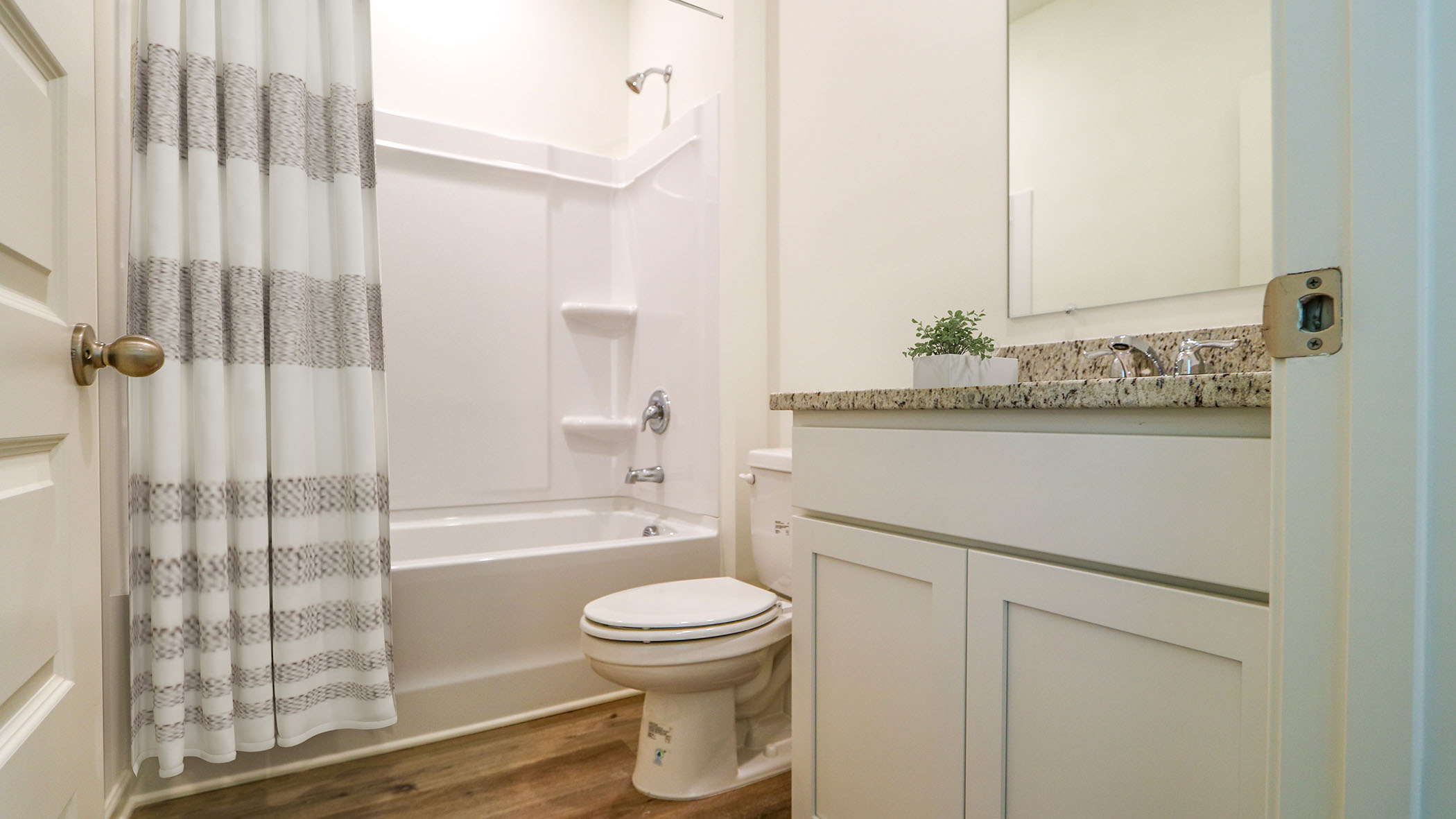 A bathroom featuring a shower curtain and a toilet, showcasing a clean and organized space for personal hygiene.