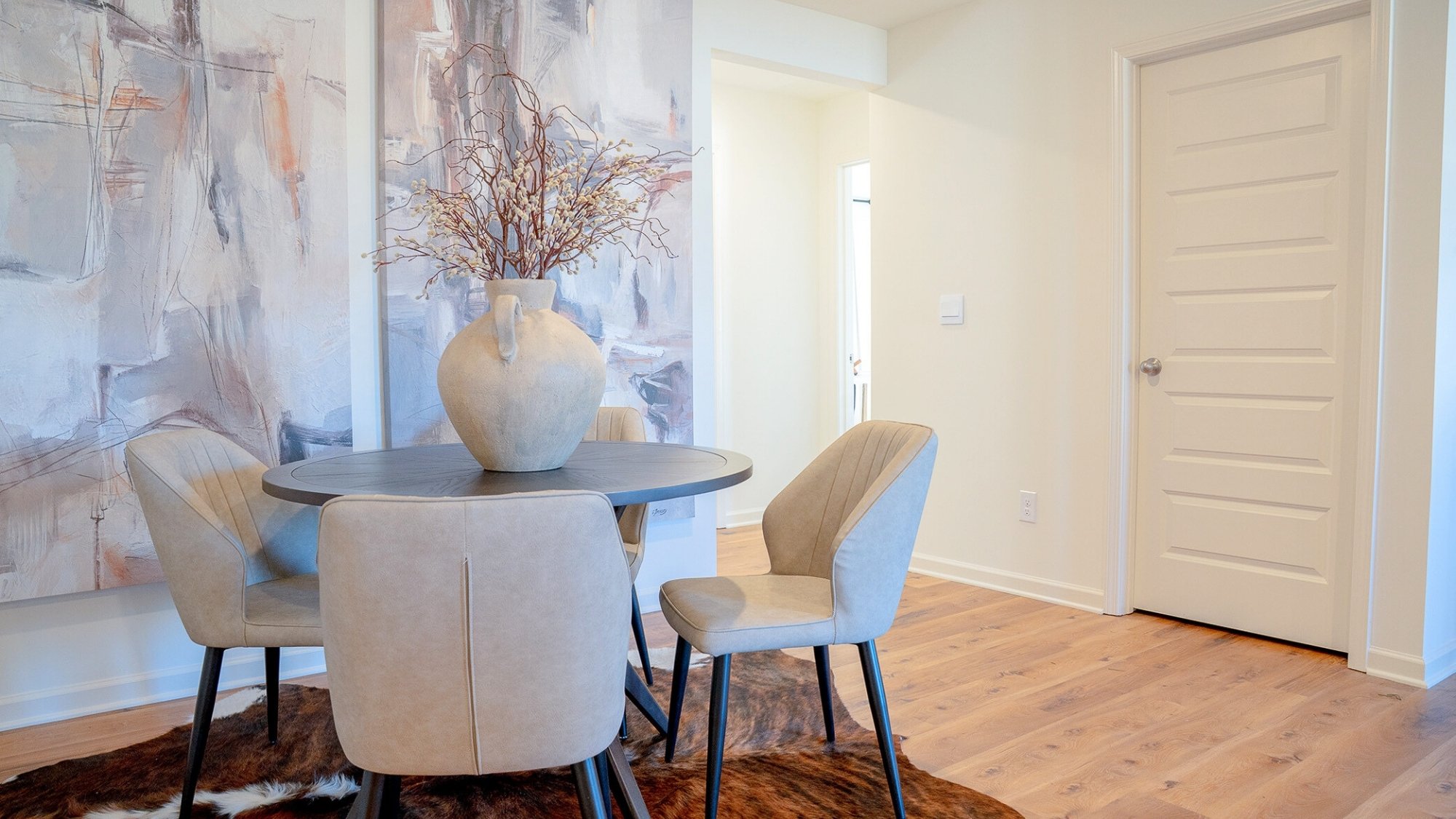 The dining nook off of the kitchen is shown here with a 4-person dining table, which is a second dining location alongside the 3-barstool sized eat-in island.