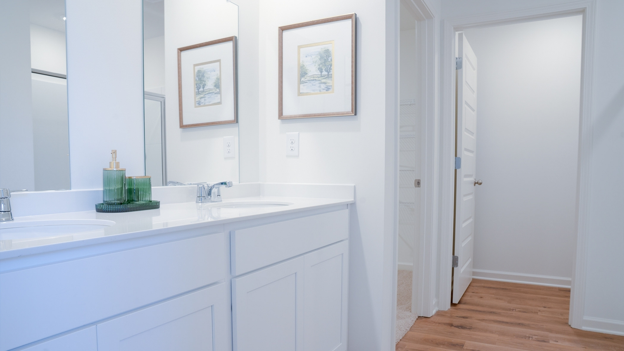 Angle looking toward the shower and garden tub, with wood-finish flooring grounding the space.