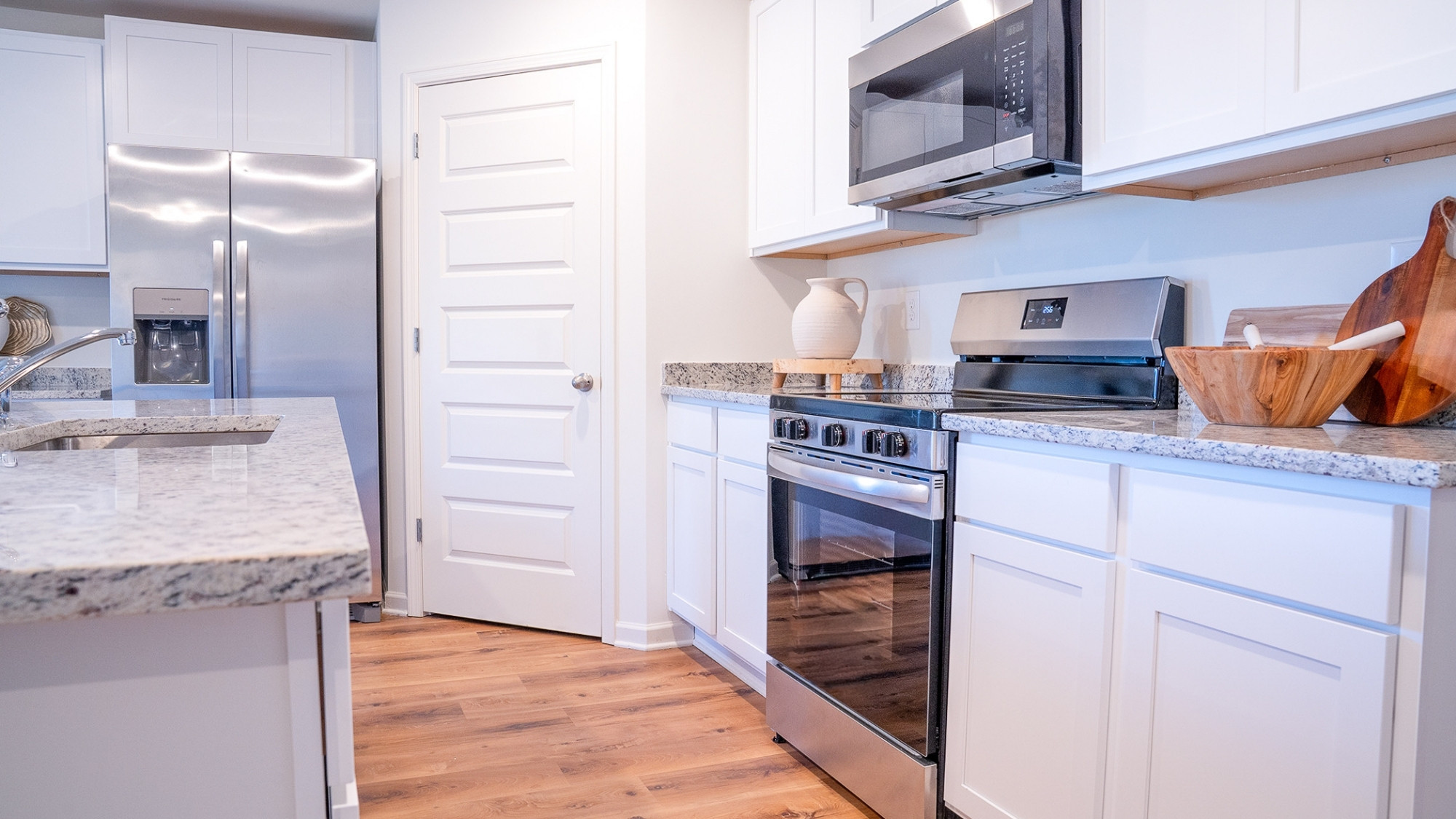 A view showcasing the kitchen and dining area, which is staged with a 4 person dining table.
