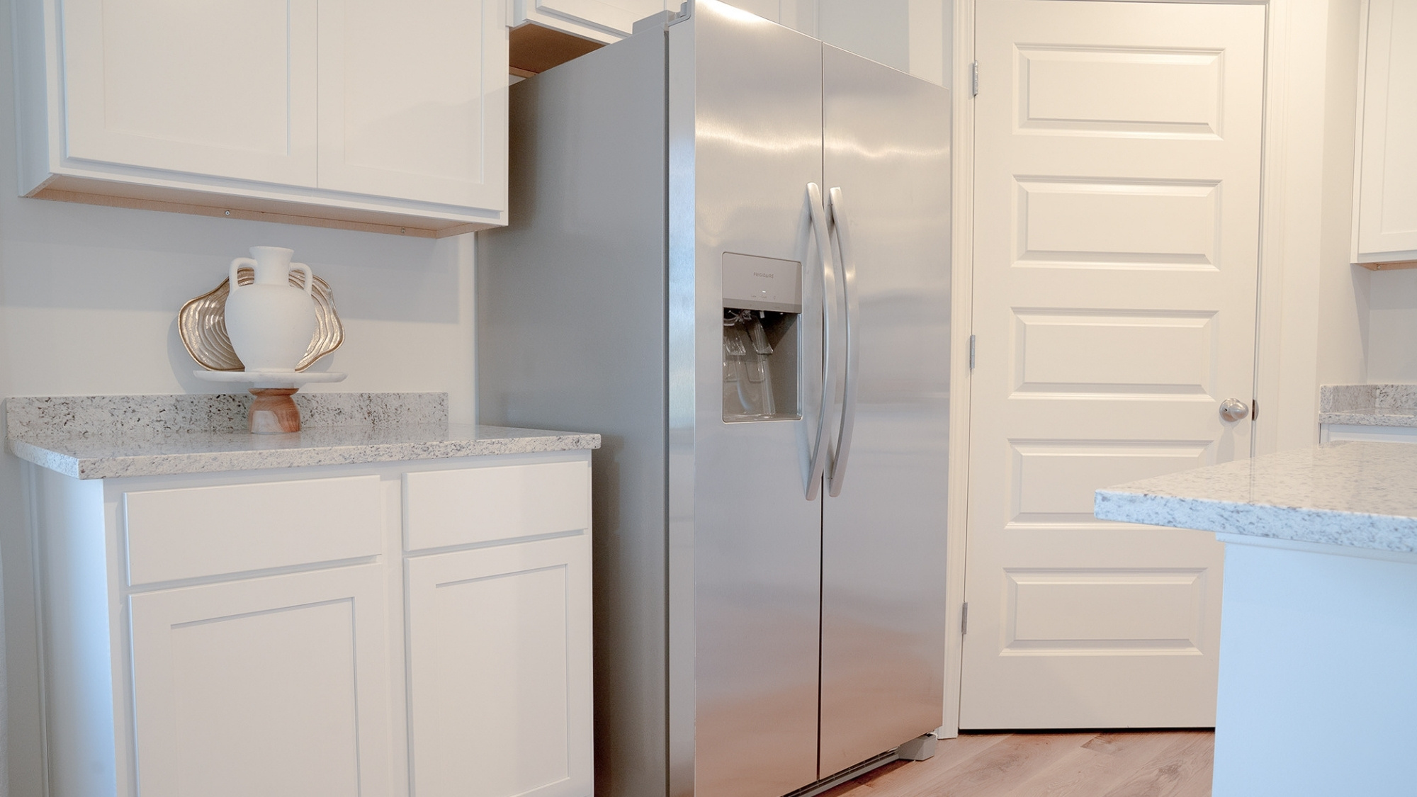 The spacious kitchen is furnished with stainless steel appliances and solid stone countertops, featuring a roomy pantry in the corner between the fridge and stove.