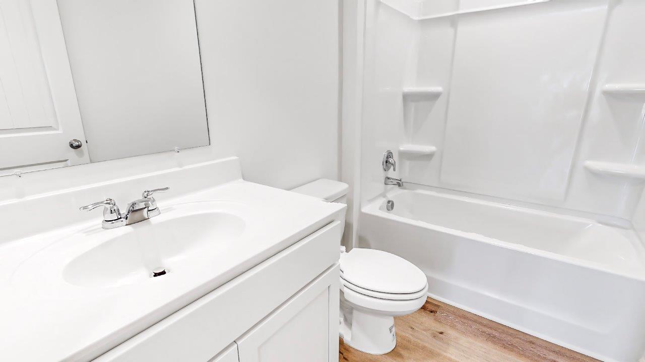 Third bathroom that features a tub – shower, toilet and vanity with a sink
