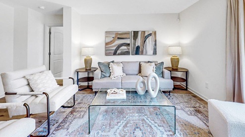 Open living room with a couch, coffee table and 2 chairs and right off the living room is the door to the primary bedroom